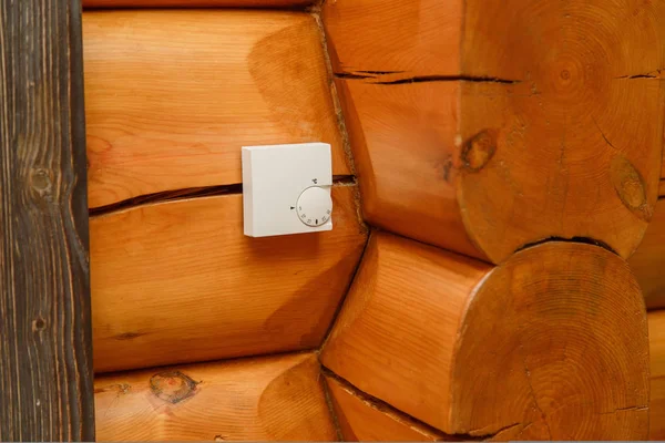 Kamer temperatuurregelaar voor verwarming en koeling op een muur in een houten huis. — Stockfoto