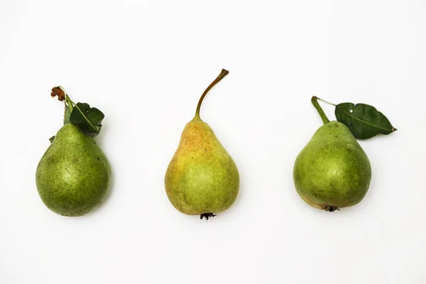 Trois poires vertes mûres avec un brin allongé dans une rangée isolée sur un fond blanc. Vue du dessus — Photo