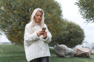 Ilık örgü kazaklı güzel sarışın kız cep telefonu kullanıyor..