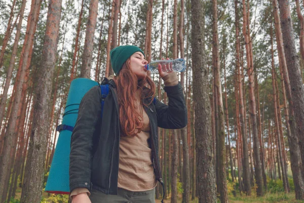 Randonneuse appréciant l'eau. Femme heureuse touriste avec sac à dos eau potable de bouteille dans la nature . — Photo