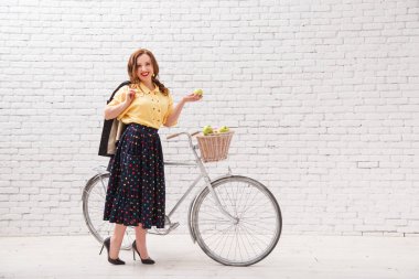 Bir kadın bir sepet elma bir ürün ile bir bisiklet sürme.