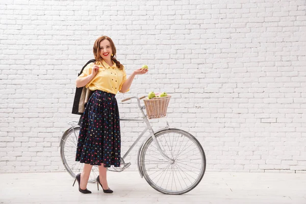 Bir kadın bir sepet elma bir ürün ile bir bisiklet sürme.