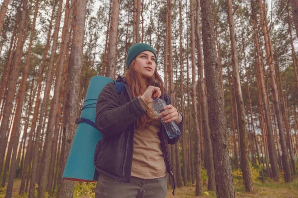 Randonneuse appréciant l'eau. Femme heureuse touriste avec sac à dos eau potable de bouteille dans la nature . — Photo