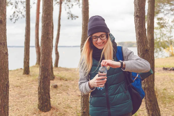 Ragazza escursionista godendo l'acqua. Donna felice turista con zaino acqua potabile da bottiglia in natura . — Foto Stock