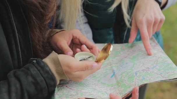 Close up view of two young tourists girlfriends trying to find direction on the map. Friends exploring the wild nature — Stock Video