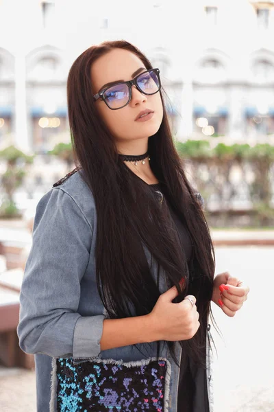 Молодая стильная женщина в черных очках и синей джинсовой куртке — стоковое фото