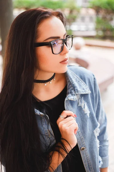 Mujer joven y elegante con anteojos negros y chaqueta de mezclilla azul — Foto de Stock