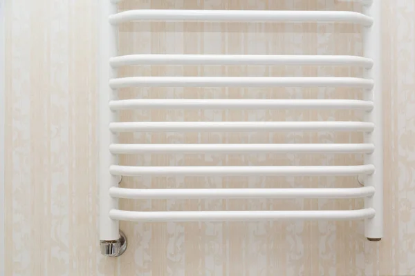 Настенный белый полотенцевой радиатор на травертиновой плитке в современной ванной комнате — стоковое фото