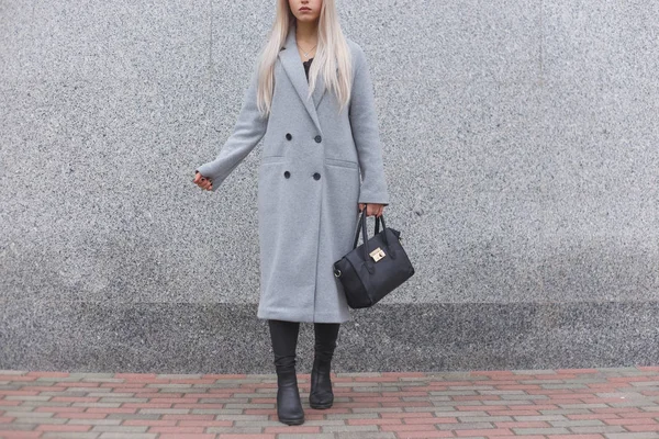 Módní žena pózuje venku, drží černá kožená taška, nosí stylové boty, elegantní kabát. Dámské modelevé koncept. — Stock fotografie