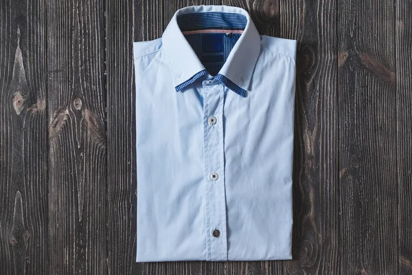 Ανδρικό κλασικό μπλε διπλωμένο βαμβακερό πουκάμισο με μακρύ ή κοντό μανίκι, σε μαύρο φόντο βάναυση. — Φωτογραφία Αρχείου