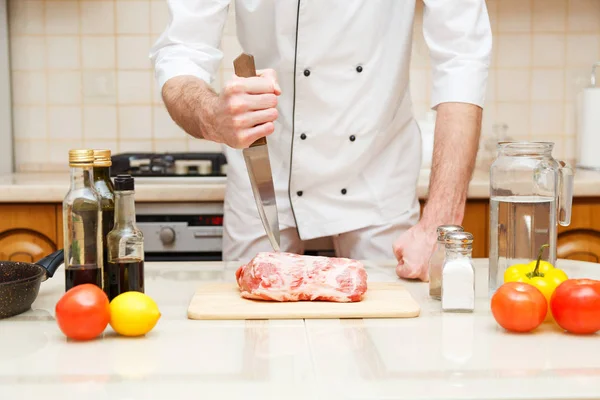 Butcher cutting meat on chopping board, professional cook holding knife and cutting meat.