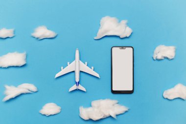Mavi arkaplanda boş ekranlı oyuncak uçak ve akıllı telefon.