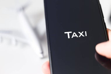 Havaalanına gitmek için cep telefonundan taksi kiralamak. Telefon ekranı yakın çekim görüntüsü