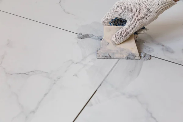 Rebocando azulejos costuras com uma espátula de borracha — Fotografia de Stock