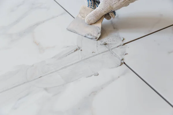 Grouting tiles seams with a rubber trowel. — Stock Photo, Image