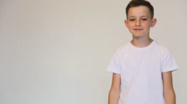 Beyaz arka planda beyaz tişörtlü mutlu çocuk kazandı.