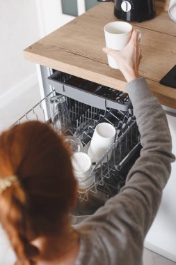 Ev işi: Bulaşık makinesine bulaşık koyan genç bir kadın