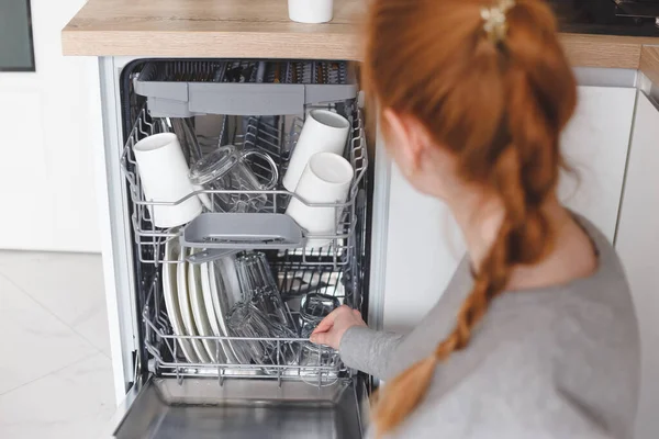 Trabajo doméstico: mujer joven poniendo platos en el lavavajillas — Foto de Stock