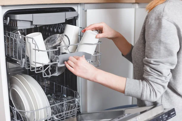 Házimunka: fiatal nő tányérokat tesz a mosogatógépbe — Stock Fotó