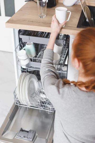 Trabajo doméstico: mujer joven poniendo platos en el lavavajillas — Foto de Stock