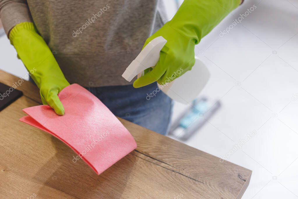 Close up woman cleaning kitchen using cleanser spray and cloth.