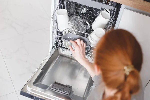 Trabajo doméstico: mujer joven poniendo platos en el lavavajillas — Foto de Stock