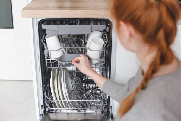Trabajo doméstico: mujer joven poniendo platos en el lavavajillas — Foto de Stock