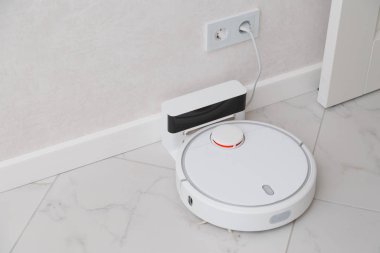 Robot elektrikli süpürge şarj ediliyor. Beyaz seramik fayanslı ve duvarlı oda