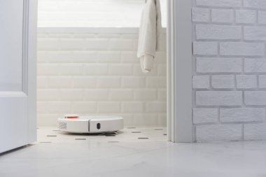 Banyoda beyaz robot elektrikli süpürge.