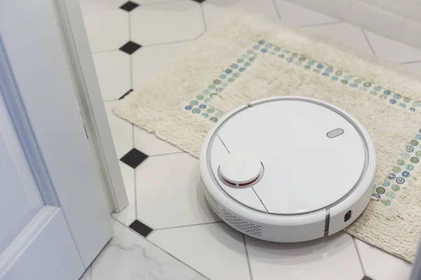 Белый робот пылесос на ковре в ванной комнате — стоковое фото