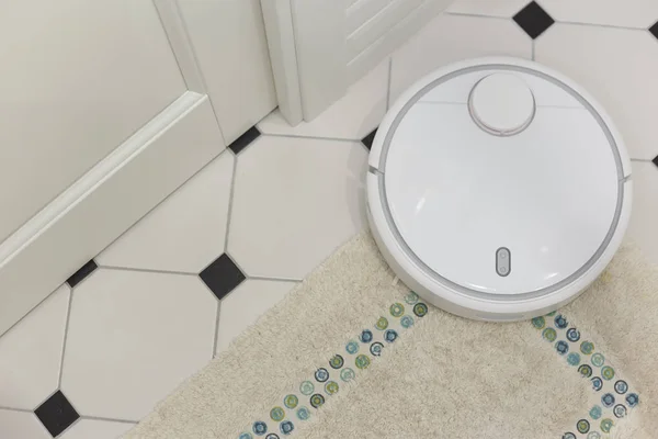 Белый робот пылесос на ковре в ванной комнате — стоковое фото
