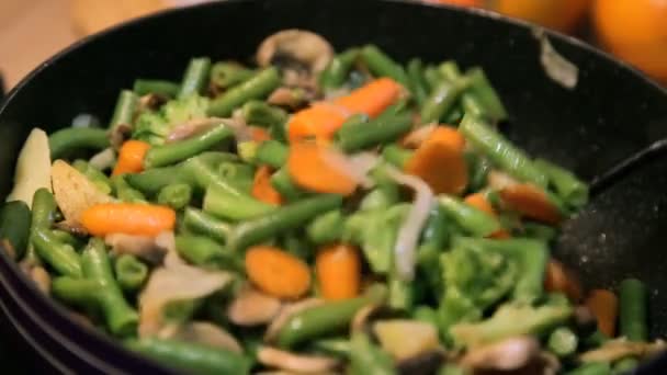 Snijbonen met champignons, broccoli, wortelen gestoofd in pan. Roeren met spatel — Stockvideo