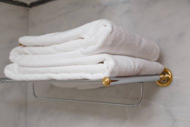 Lüks metal raf mermer banyoda temiz havlu yığını.
