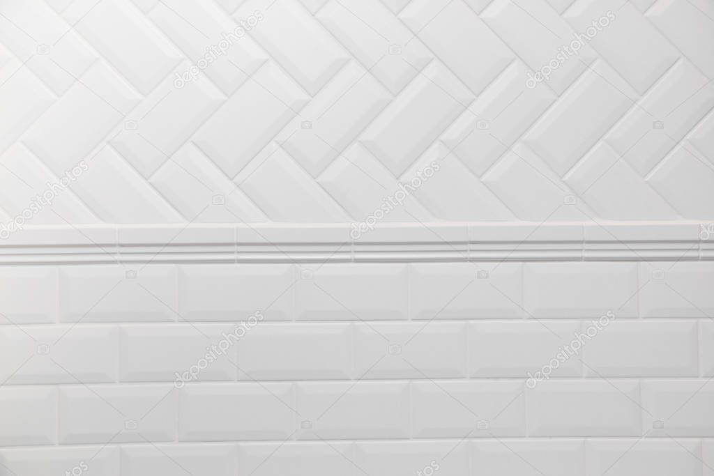 Bathroom wall tiled in scandinavian style with white grouting. Connection two different tile layouts herringbone and brick wall