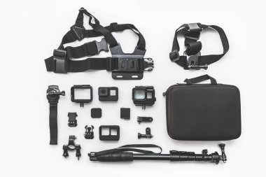 Flat lay of action camera with accessories on white background top view.