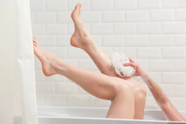 Kobieta w kąpieli, mycia nóg w wannie z dużą ilością pianki kąpiel z bąbelkami. nogi piękne Młoda kobieta w kąpieli w łazience. — Zdjęcie stockowe