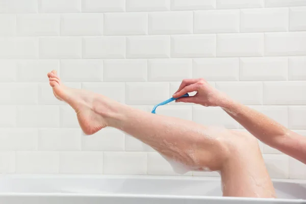Kobieta w łazience goli nogi brzytwą. Zbliżenie ręki brzytwą. — Zdjęcie stockowe