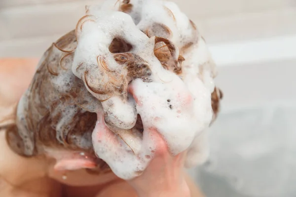 Roodharige jonge vrouw wassen haar haar met shampoo zitten in bad — Stockfoto