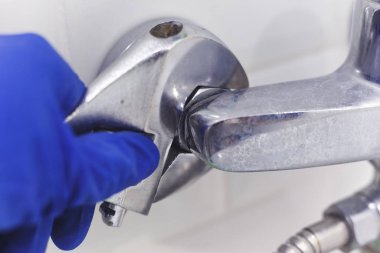 Tesisatçı servis duş karıştırıcı musluğu için boru anahtarı kullanıyor