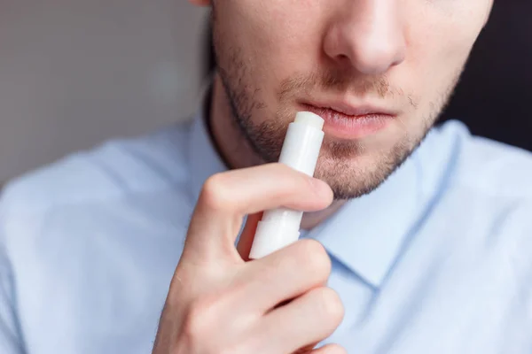 Uomo che applica rossetto igienico sulle labbra per ravvivare le labbra screpolate ed evitare secchi, primo piano — Foto Stock