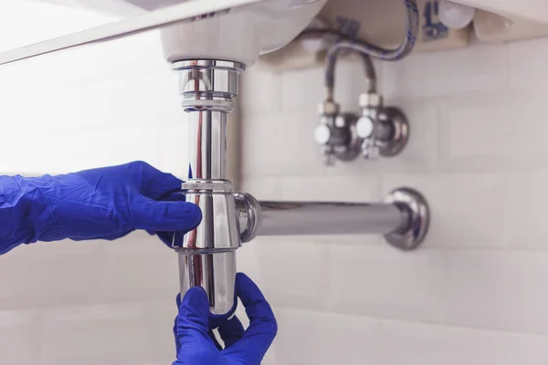 Vízvezeték szerelő javítja és karbantartja króm szifon alatt a mosdókagyló. Vízvezeték szerelő munka a fürdőszobában, vízvezeték szerelés és telepítés koncepció — Stock Fotó
