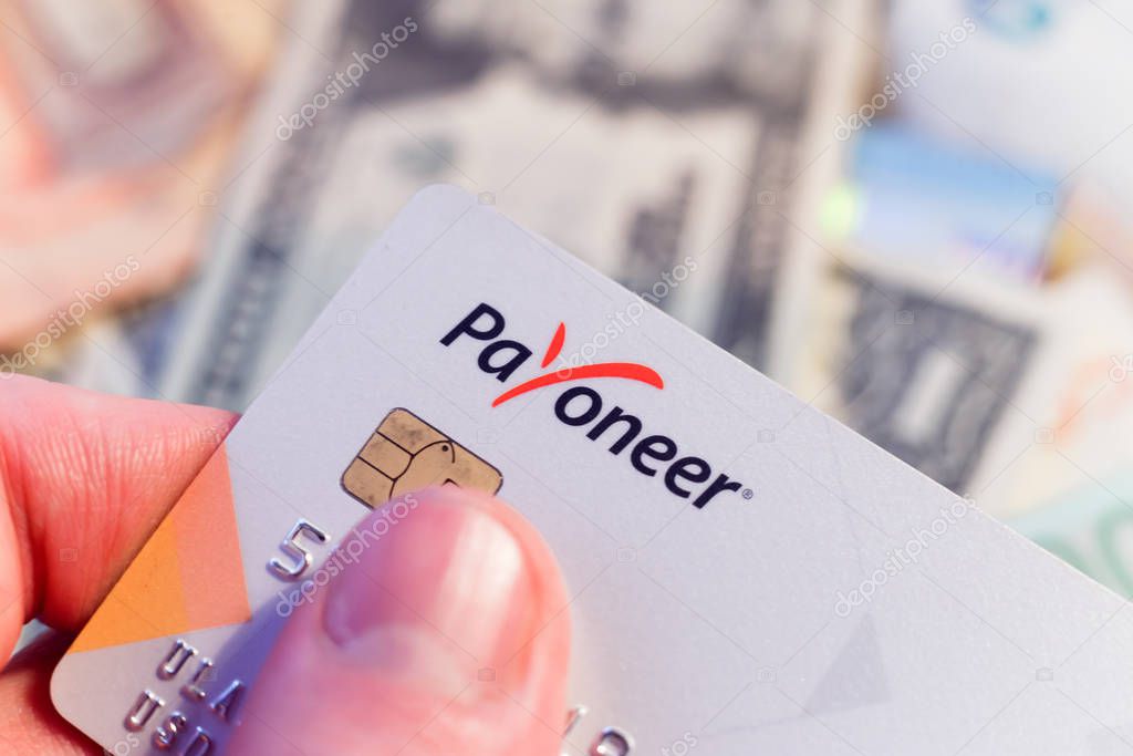 Minsk, Belarus - January 3, 2019: Prepaid payment card Payoneer and money in background.