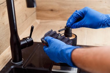 Adam bulaşık deterjanıyla şişe kapağını süngerle temizliyor..