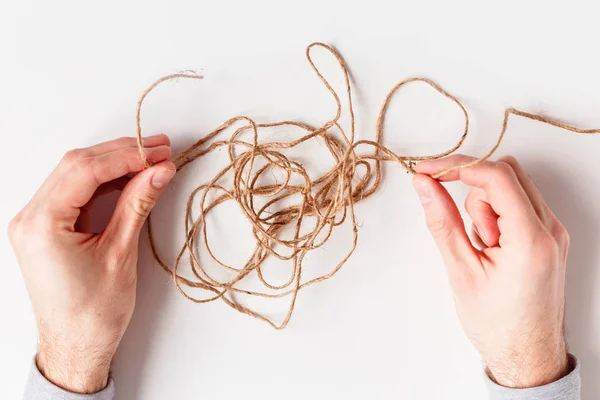 Man untangles a tangled thread. Top view isolated on a white background.