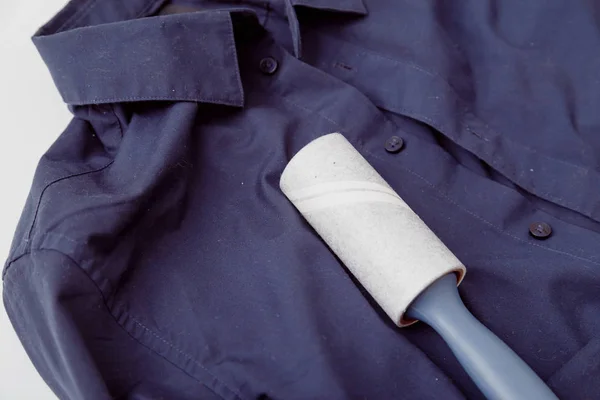 Sticky roller on dark color shirt with static cling, covered by dust, lint, fluff and hairs