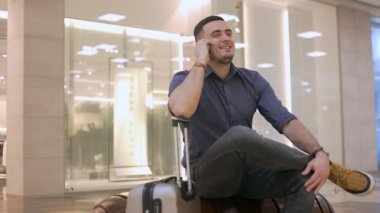Erkek yolcu havaalanında cep telefonuyla konuşuyor. Ailenle ya da sevdiklerinle neşeli bir sohbet.