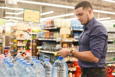 man selecting or buying a bottle of mineral drinking or distilling water at the shopping store clipart
