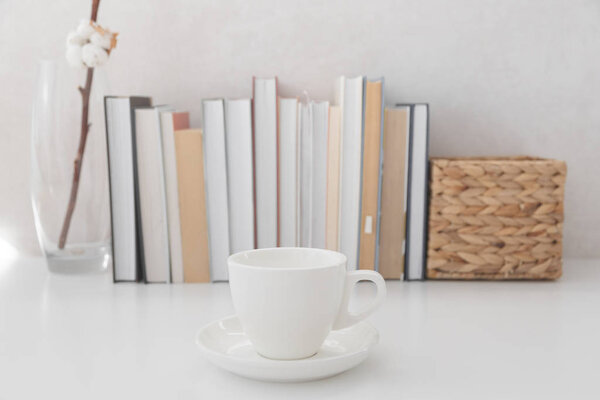 Bookshelf with books and cup of hot beverage in focus.