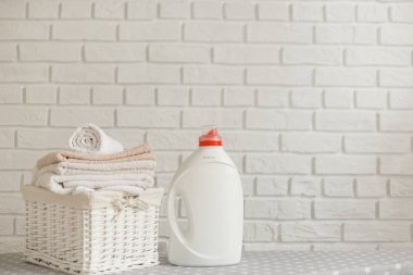 Deterjan jeli beyaz plastik şişe ve renkli elbiseli hasır sepet. Temizlik ve çamaşır konsepti.
