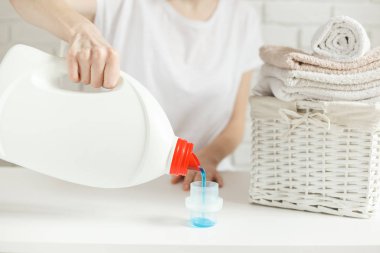 Kadın kapağa deterjan döküyor, yakın plan. Çamaşır konsepti